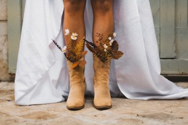 Bottes beige ornées de feuilles et de fleurs, portées avec une robe blanche.