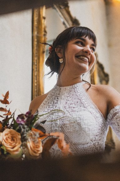 Femme souriante en robe de mariée tenant un bouquet de fleurs dans un cadre élégant.